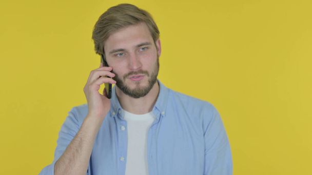 Casual młody człowiek rozmawia na telefon na żółtym tle - Zdjęcie, obraz