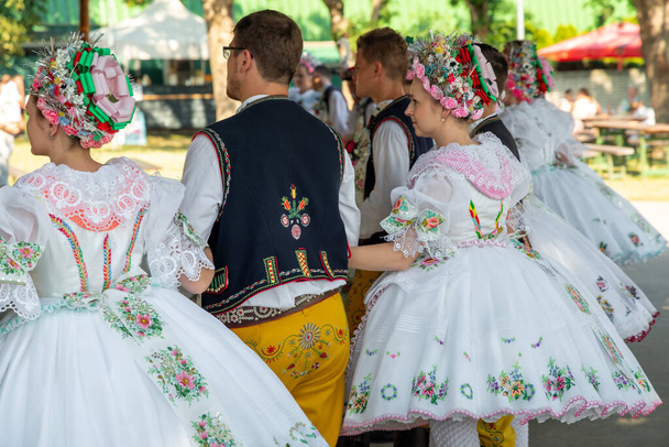Rakvice, Cseh Köztársaság - 2021. június. Gyönyörű nők és férfiak táncosok egy ünnepségen.Hagyományos morva ünnep. Hagyományos morva népviseletben parádézó fiatalok. - Fotó, kép