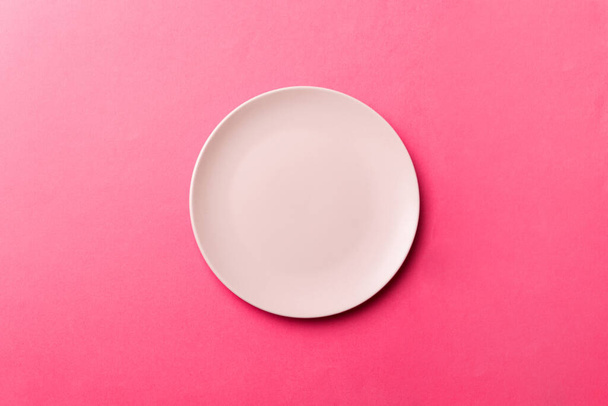 Top view of isolated of colored background empty round pink plate for food. Empty dish with space for your design. - Foto, afbeelding