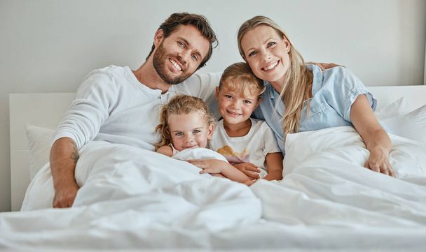 Family, children and bed with a girl, sister and parents in the bedroom of a home to relax together in the morning. Portrait, love and smile with a happy mother, father and daughter siblings bonding. - Φωτογραφία, εικόνα