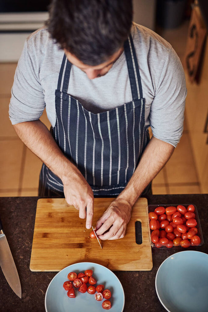 Nyári salátát szeletel magának. Nagy látószögű felvétel egy azonosítatlan fiatalemberről, aki zöldségeket aprít otthon a konyhájában. - Fotó, kép