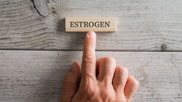 Mužská ruka umístění dřevěný kolík s Estrogen znamení na to přes bílé dřevěné pozadí. - Fotografie, Obrázek