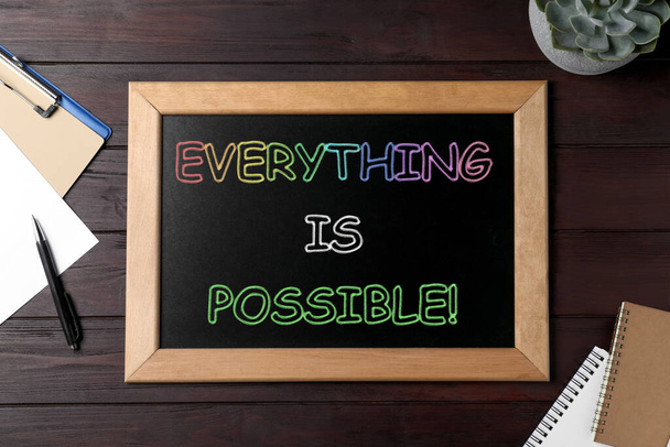 Small chalkboard with motivational quote Everything is possible, plant and stationery on wooden table, flat lay - Valokuva, kuva