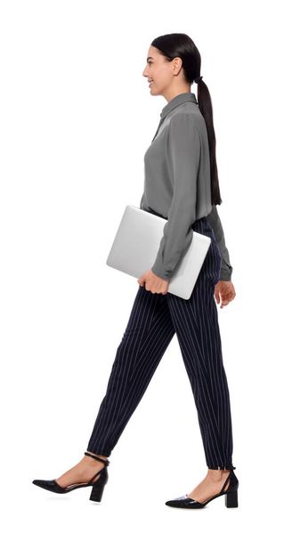 Young businesswoman with laptop walking on white background - Photo, Image