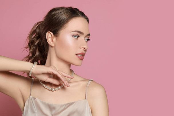Young woman wearing elegant pearl jewelry on pink background, space for text - Φωτογραφία, εικόνα