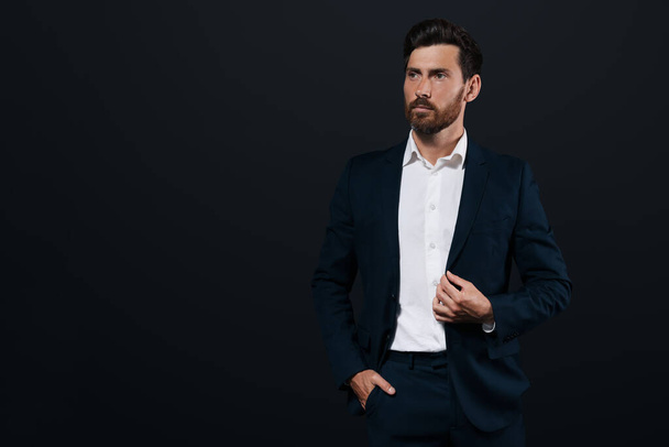 Portrait of handsome bearded man in suit looking away on black background. Space for text - Foto, immagini