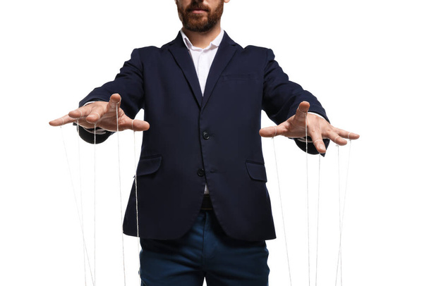 Man in suit pulling strings of puppet on white background, closeup - 写真・画像