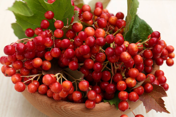 Bowl with tasty viburnum berries on white wooden table, closeup - Zdjęcie, obraz