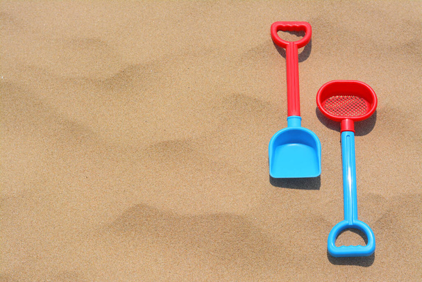 Plastic shovel and sieve on sand, space for text. Beach toys - Фото, зображення