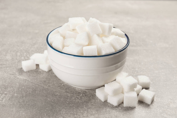 Bowl with sugar cubes on grey table, closeup - Foto, imagen