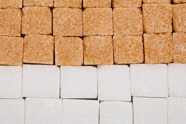 White and brown refined sugar cubes as background, top view - Foto, afbeelding
