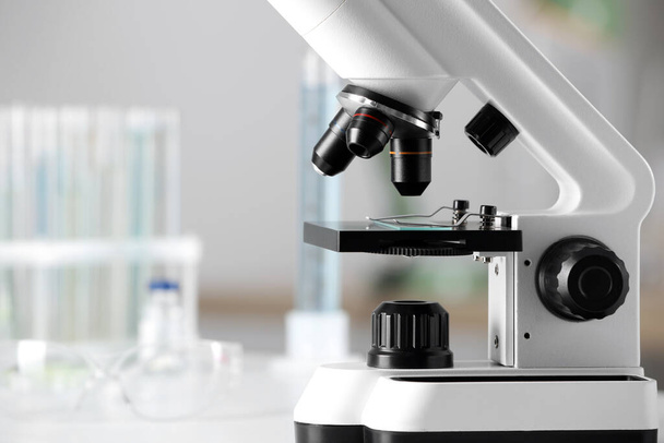 Modern medical microscope on white table in laboratory, closeup. Space for text - Fotó, kép