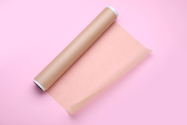 Roll of baking paper on pink background, top view - Φωτογραφία, εικόνα