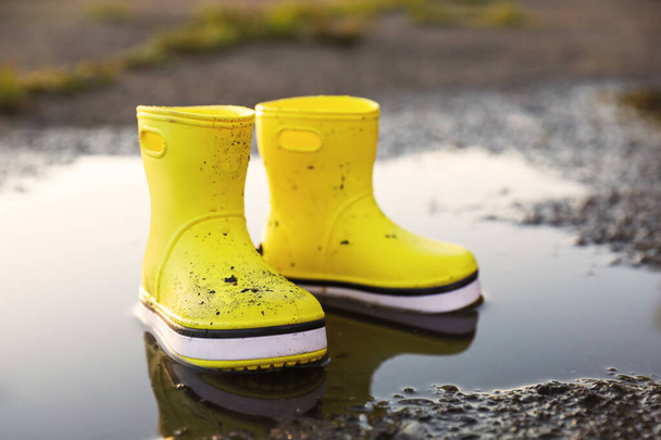 Yellow rubber boots in puddle outdoors. Autumn walk - Fotografie, Obrázek