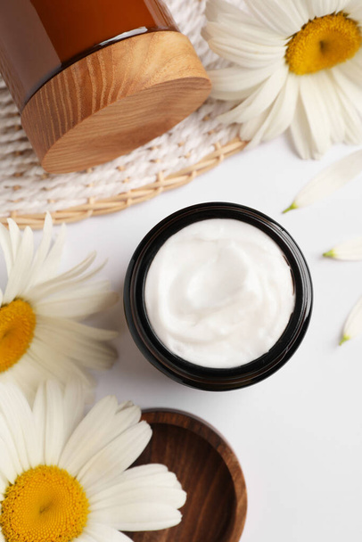 Flat lay composition with jar of face cream and beautiful flowers on white background - Zdjęcie, obraz