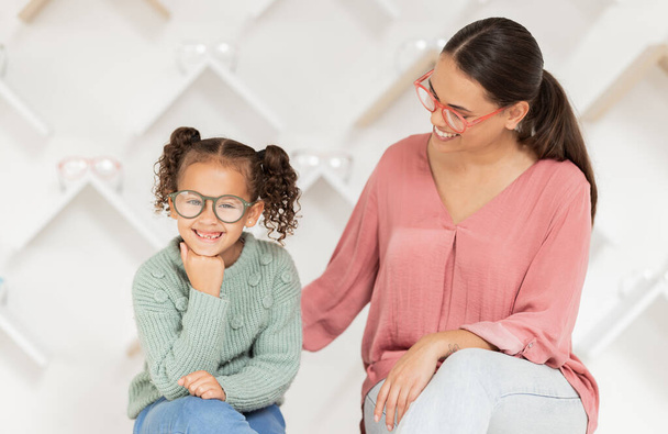 Shopping, vision and glasses with mother and girl buying eyewear together in retail store. Woman, daughter and consumer optics while buy eyeglasses in optometry shop for eye health and eye care. - Photo, Image