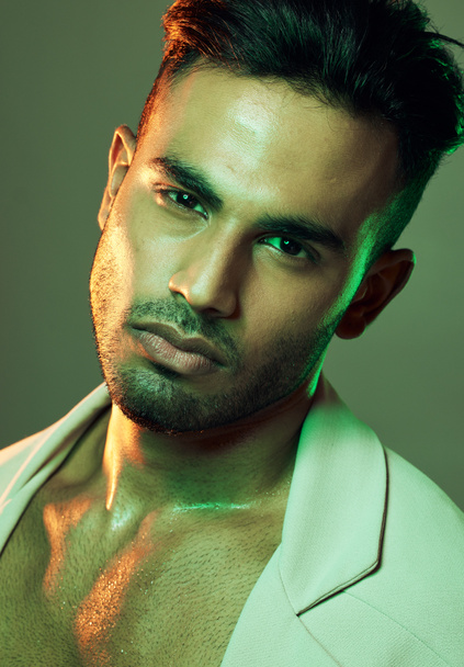 Mode, groen licht en portret van sexy man uit India in studio achtergrond creatieve shoot. Schoonheid, neon licht en professioneel mannelijk model, Indiase man en ernstig gezicht in de mens gezondheid en cosmetica. - Foto, afbeelding