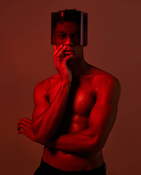 Cyberpunk, γυαλιά και κόκκινο νέον μαύρο άνδρα με αισθητικό φωτισμό, δημιουργική σκιά σώματος και φουτουριστικό sci fi μόδα. Μελλοντική μάσκα φαντασίας, δημιουργικότητα ομορφιάς και μοντέλο z με σέξι φως σκιάς. - Φωτογραφία, εικόνα