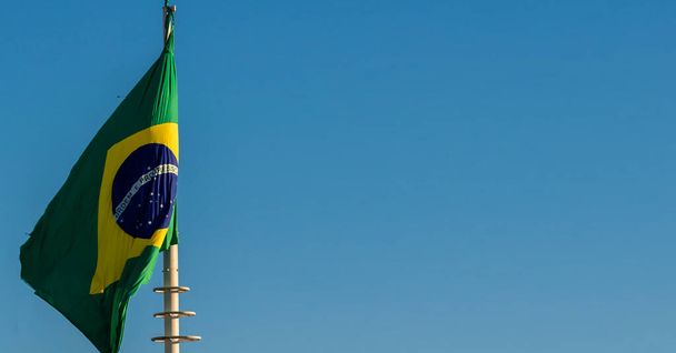 Brazilian national flag on a flagpole in front of blue sky in Brazil - Foto, Imagem