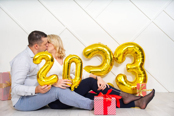 Young couple having romantic date on Christmas eve with 2023 golden foil inflatable balloons. Christmas and 2023 New Year Holidays concept. - Fotoğraf, Görsel