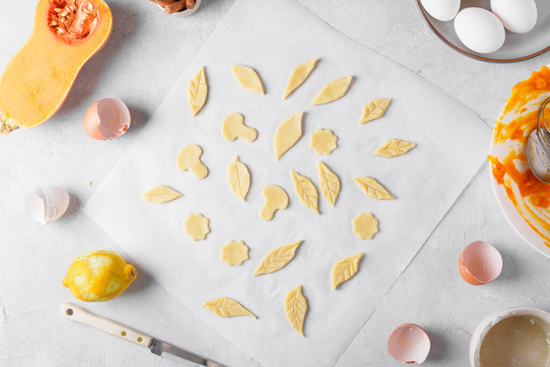 Cooking thanksgiving pumpkin pie. Leaves of dough decorative elements for decorate thanksgiving pumpkin pie on a gray kitchen table, lifestyle, top view, flat lay, recipe - Photo, Image
