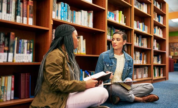 Reuniéndose en su proyecto de grupo. dos estudiantes universitarios que trabajan juntos en la biblioteca del campus - Foto, imagen