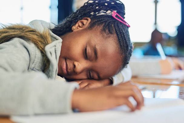 Her little brain can only carry so much. an elementary school girl sleeping on her desk in class - Foto, afbeelding