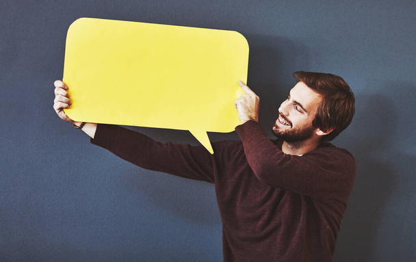 Express yourself. Studio shot of a young man holding a speech bubble against a grey background - Foto, Bild