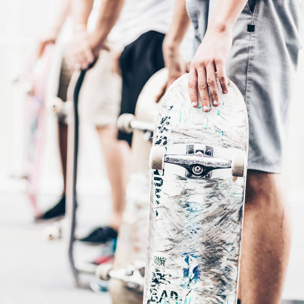 Jovens skatistas a andar de skate na rua. Grupo de amigos em pé em uma fileira com skates em suas mãos. Vida urbana. Subcultura da juventude
. - Foto, Imagem