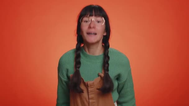 クォーレル。緑のセーターに不満を持つ女性が刺激と不満を手をジェスチャーし、失敗のために叱責を非難し、なぜ起こったのかを尋ねる。若いです女の子孤立した上のオレンジスタジオの壁の背景 - 映像、動画