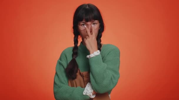 I am watching you. Latin woman in green sweater pointing at her eyes and camera, show I am watching you gesture, spying on someone. Young adult girl isolated alone on orange studio wall background - Footage, Video