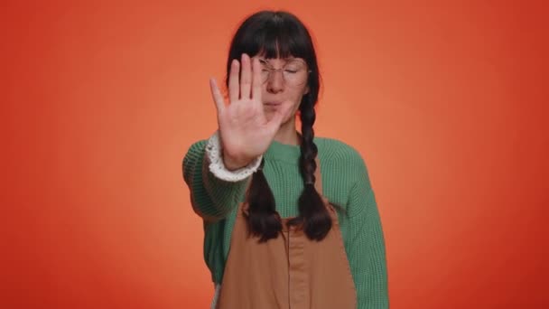 Kein Halt. Ernsthafte erwachsene Frau sagt Nein, hält die gefalteten Hände in Stop-Gefahr-Geste, warnt vor dem Ende, verbietet den Zugang zu Kommunikation, Körpersprache. Junge Mädchen auf orangefarbenem Hintergrund - Filmmaterial, Video