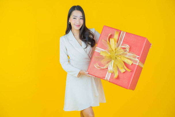 Portrait beautiful young asian woman smile with red gift box on color background - Foto, afbeelding