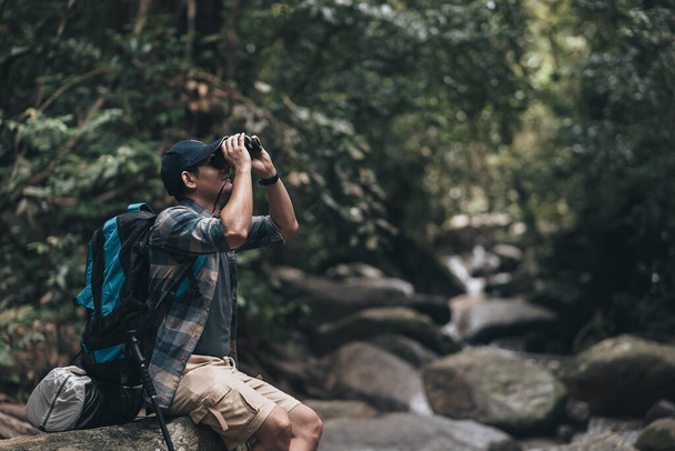 Hikers use binocular to see animals and view landscape  with backpacks in the forest. hiking and adventure concept. - Photo, Image