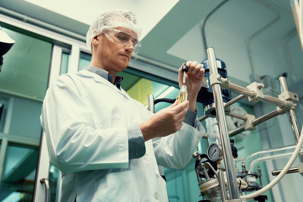 Ein Wissenschaftler oder Apotheker extrahiert CBD-Hanföl für medizinische Zwecke in einem Labor. Alternative Medizin auf Cannabisbasis, hergestellt aus einer Cannabis-Extraktionsmaschine. - Foto, Bild