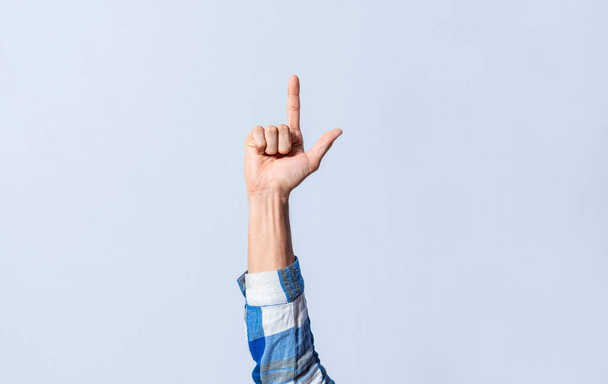 Handbewegungen mit dem Buchstaben L in Gebärdensprache auf einem isolierten Hintergrund. Die Hand des Mannes gestikuliert mit dem Buchstaben L des Alphabets isoliert. Buchstaben des Alphabets in Gebärdensprache - Foto, Bild