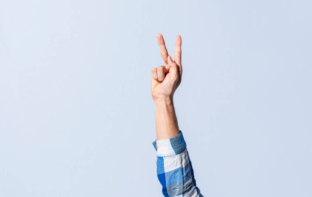Hand gesturing the letter K in sign language on an isolated background. Man's hand gesturing the letter K of the alphabet isolated. Letters of the alphabet in sign language - Fotó, kép
