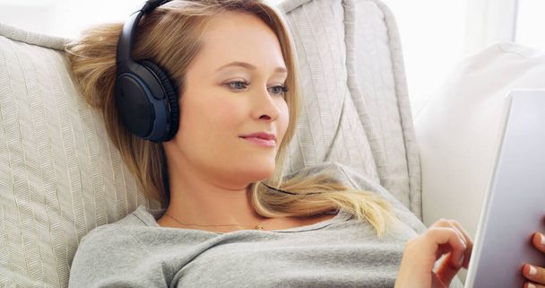 Eu adoro navegar através de diferentes tipos de música. uma jovem atraente ouvindo música com fones de ouvido em casa - Foto, Imagem