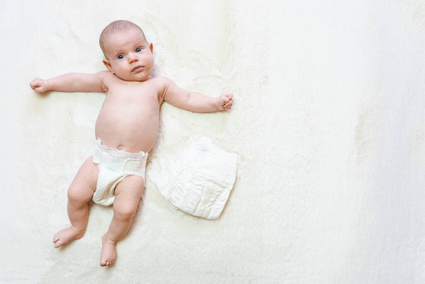 Pelenkás lány újszülött baba transzparens. Gyermek ellátás fehér háttér. Boldog aranyos baba pelenkában. Újszülött ellátás, hasfájás, fogak, újszülött napi kezelés - Fotó, kép