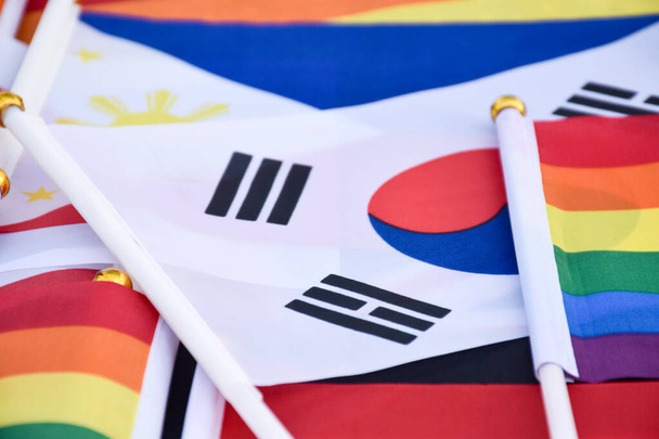 Banderas de arco iris y banderas de muchos países se colocan en el suelo juntos, concepto para la celebración de los géneros lgbtq + en el mes de orgullo en todo el mundo, enfoque suave y selectivo. - Foto, Imagen