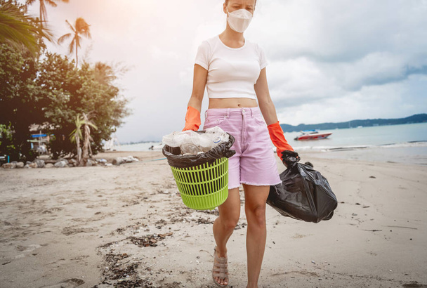 A female ecologist volunteer cleans the beach on the seashore from plastic and other waste. - Fotoğraf, Görsel