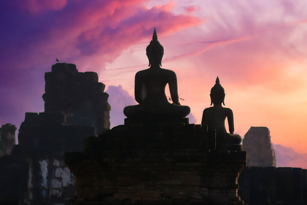 Aspecto de silueta de antiguas estatuas de Buda frente a una colorida nube de la mañana y el cielo en Wat Pra Pai Luang, Sukhothai Historical Park, Tailandia - Foto, imagen