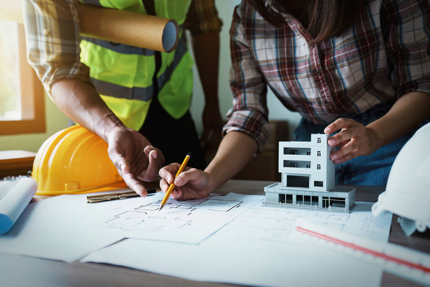 Инженеры консультируют команду по проектированию архитектурной структуры для клиентов с чертежами и строительными моделями для работы в офисе. - Фото, изображение