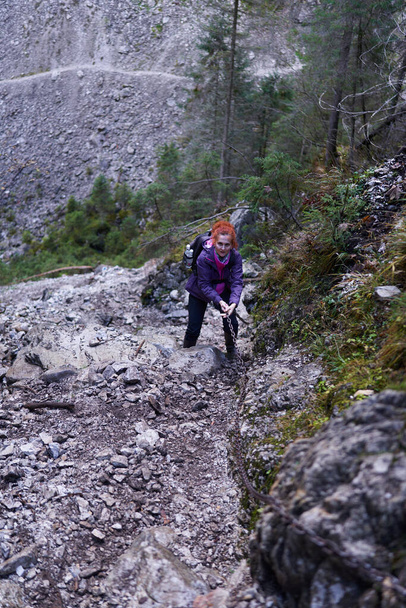 Sırt çantalı bir kadın dağda yürüyüş parkurunda yürüyor. - Fotoğraf, Görsel