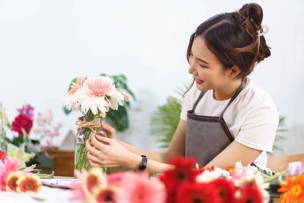 Concepto de la tienda de flores, floristería femenina está decorando flores coloridas florero por cuerda de cáñamo en forma de arco. - Foto, Imagen
