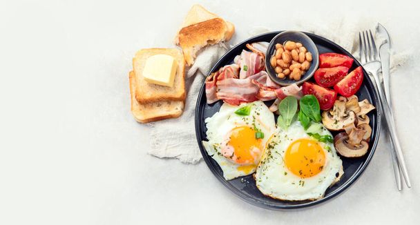 Full English breakfast with fried egg, sausage, bacon and toast on grey background. Top view, copy space - Foto, Imagem