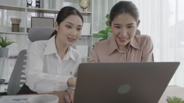 Enthusiastic office employees celebrate their success in office workplace. Colleagues collaborating at a table with a laptop and achieving achievement. Two businesswomen happy with their work. - Footage, Video