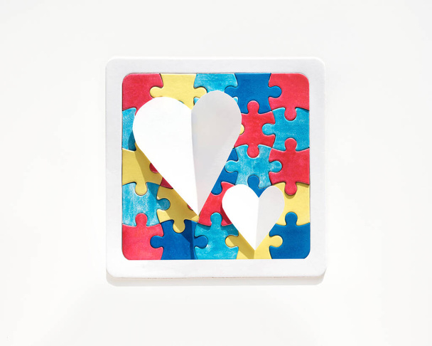 Den autismu, Světový den autismu, rámeček s kousky skládanky a papírovými srdci. Nápis, tapeta, pozadí pro leták, plakát ke kampani na zvyšování povědomí o zdravotnictví pro autismus - Fotografie, Obrázek
