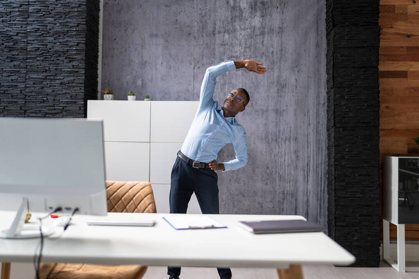 Exercice d'étirement des bras debout près du bureau au bureau - Photo, image