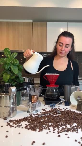 Siyah saçlı güzel genç bir kadın kahve çiçeğinin yanındaki masaya farklı profesyonel kahve ekipmanları ve kahve yapmak için farklı aksesuarlar döker. - Video, Çekim